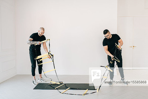 Fitness instructors preparing agility ladder in studio