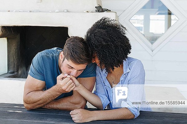 Mann küsst im Strandhaus die Hand einer Frau