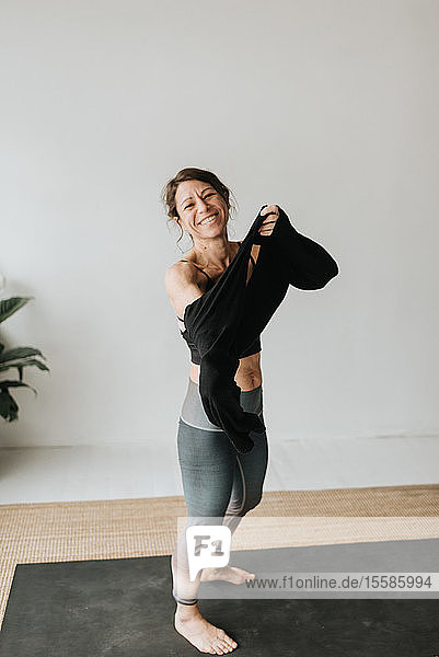 Frau zieht Pullover im Yogastudio an