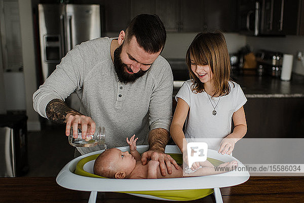 Junger Mann und Tochter baden Baby-Sohn in Küche