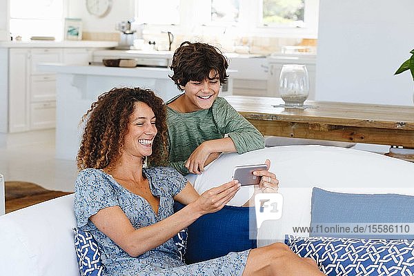 Mutter und Sohn lächeln bei Textnachricht auf dem Handy