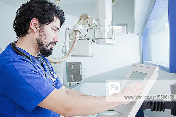 Junger männlicher Radiologe am Bedienpult eines Röntgengerätes in der radiologischen Abteilung