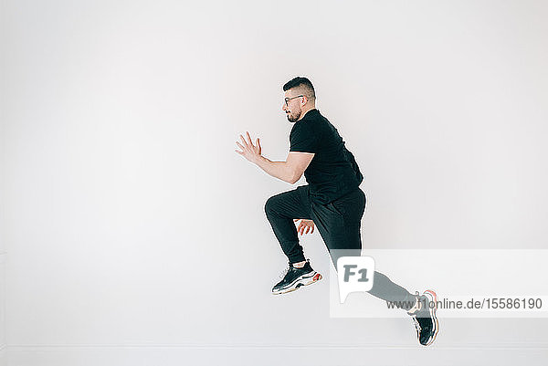 Man doing high jump against white wall