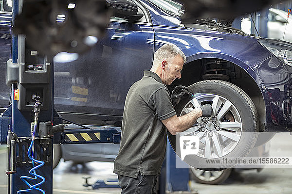 Engineer checking brakes in car service centre