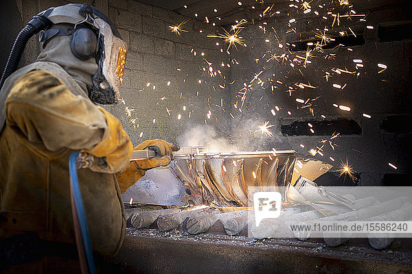 Worker cutting up scrap titanium aircraft parts in titanium recycling plant