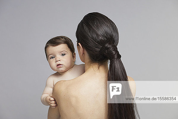 Baby schaut der Mutter über die Schulter