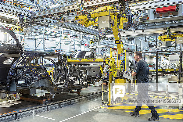 Worker inserting dashboard into car in car factory