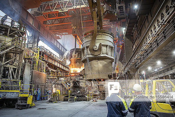 Steelworkers looking on during steel pour in steelworks
