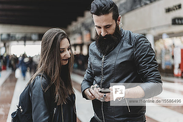 Couple using smartphone in station