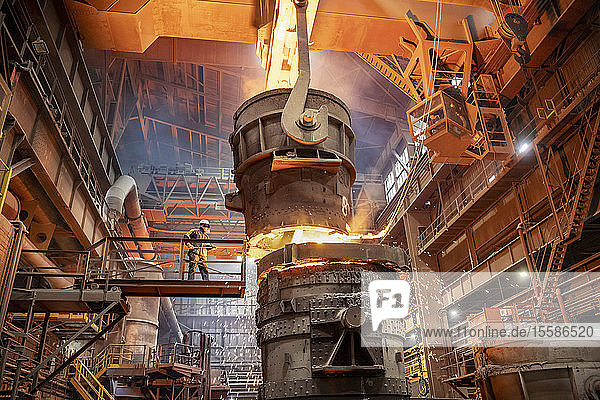 Steelworker starting molten steel pour in steelworks