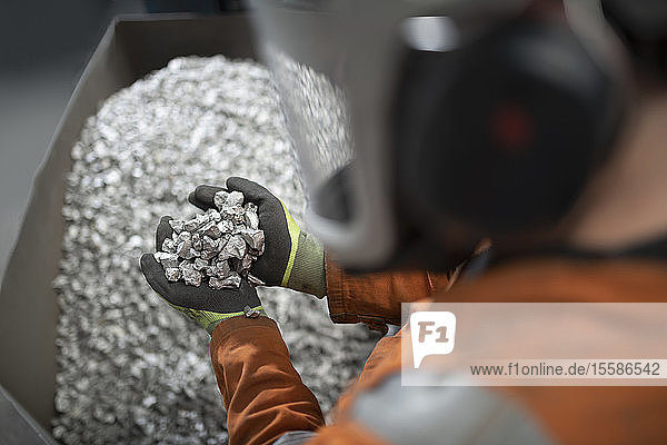 Close up of worker holding titanium sample in crushing plant in titanium recycling plant