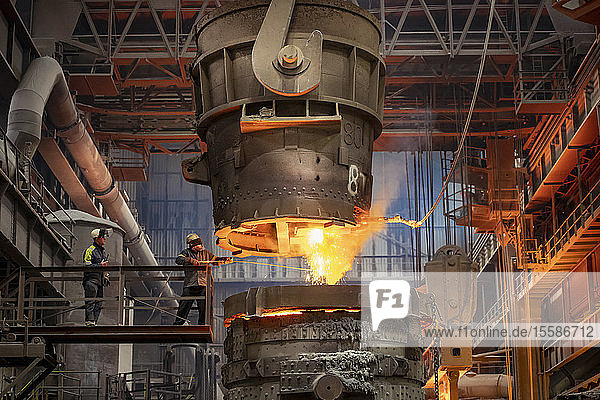 Steelworker starting molten steel pour in steelworks