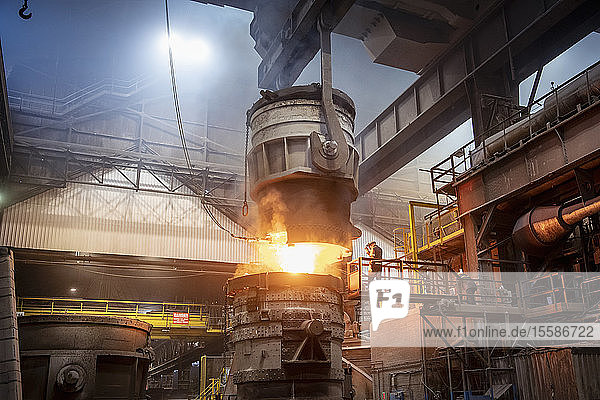 Steelworkers pouring molten steel in steelworks