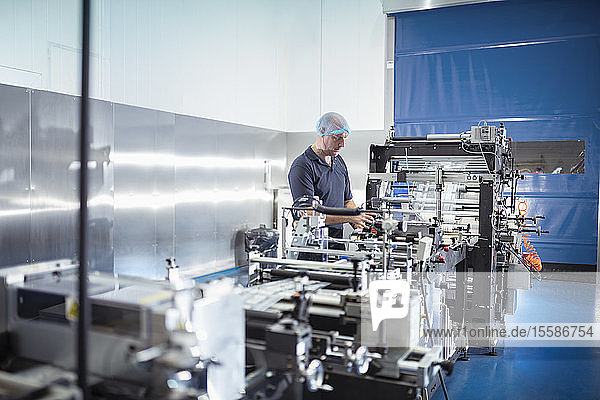 Worker with food packaging machine in print factory