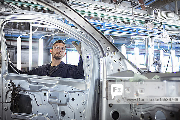 Worker inspecting car body in car factory