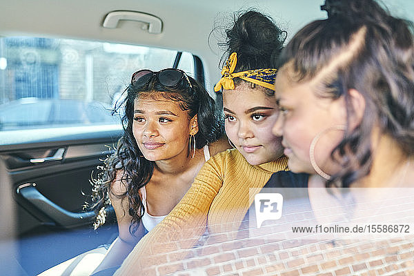 Young woman and teenage sisters in back seat of car
