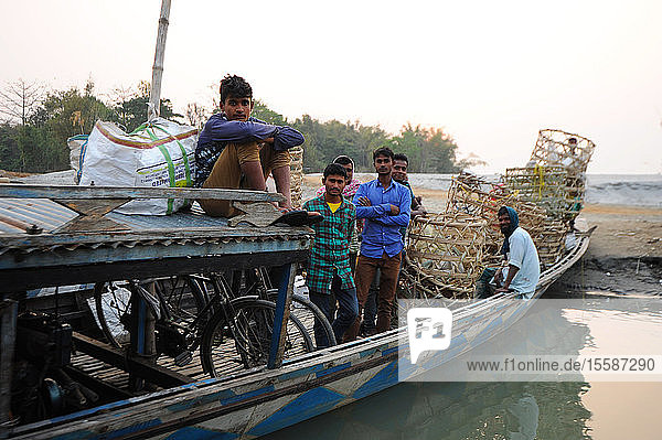 Village men with baskets and bicycles  on the local village ferry waiting to cross the Brahmaputra river  Assam  India