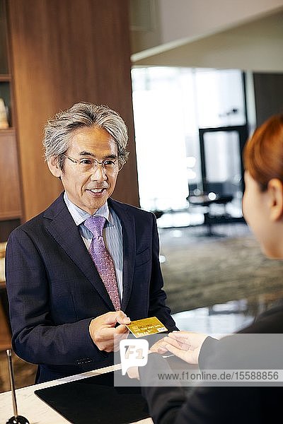 Älterer Geschäftsmann beim Einchecken im Hotel