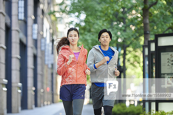 Young Japanese couple running downtown Tokyo