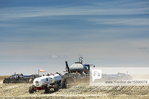 Air seeder in field with white ammonia tanks  near Beiseker; Alberta  Canada