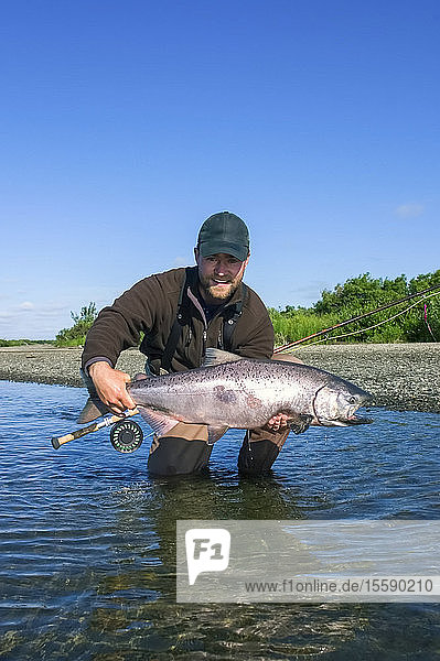 Fliegenfischer posiert mit gefangenem Chinook-Lachs entlang des Kanektok River in Alaska