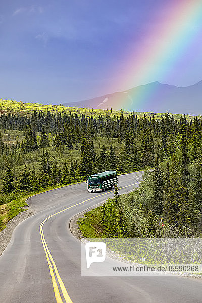 A tour bus travels the Denali Park Road under a rainbow in Denali National Park and Preserve in Interior Alaska; Alaska  United States of America