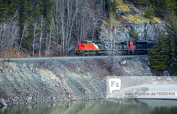 Canadian National Railway train traveling beside a lake; Terrace British Columbia Canada