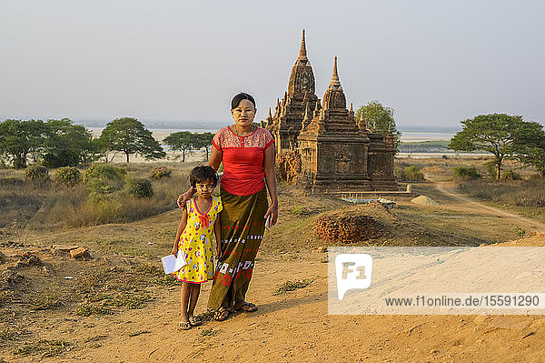 Porträt einer Mutter und ihrer Tochter beim Verkauf von Zeichnungen  im Hintergrund ein buddhistischer Tempel; Bagan  Mandalay Region  Myanmar