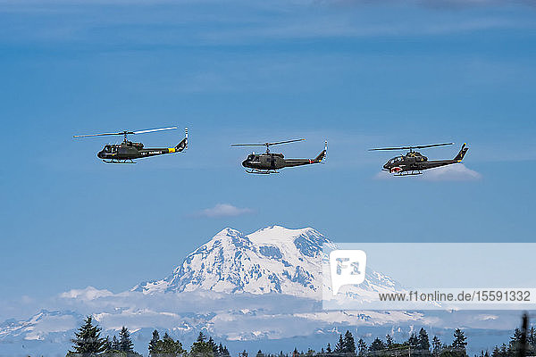 Zwei UH-1 Huey-Hubschrauber und ein AH-1 Cobra fliegen in Formation mit Mount Rainier im Hintergrund  Olympic Air Show 2019  Olympic Airport; Olympia  Washington  Vereinigte Staaten von Amerika