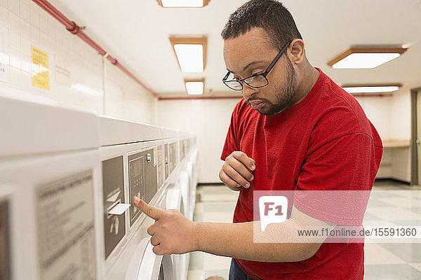 Afroamerikanischer Mann mit Down-Syndrom bezahlt für Wäsche im Waschraum