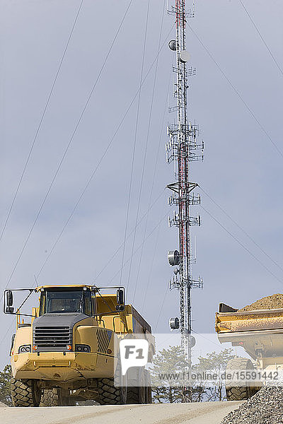 Erdbewegungsmaschine auf einer Baustelle mit einem Mobilfunkturm im Hintergrund