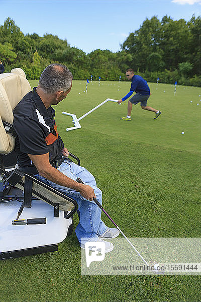 Man with spinal cord injury in an adaptive cart at golf putting green