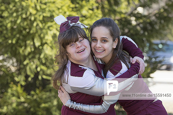 Porträt von zwei Cheerleadern  die sich umarmen  einer davon mit Down-Syndrom