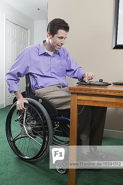 Tetraplegiker im Rollstuhl mit Rückenmarksverletzung nutzt sein elektronisches Tablet für E-Mails