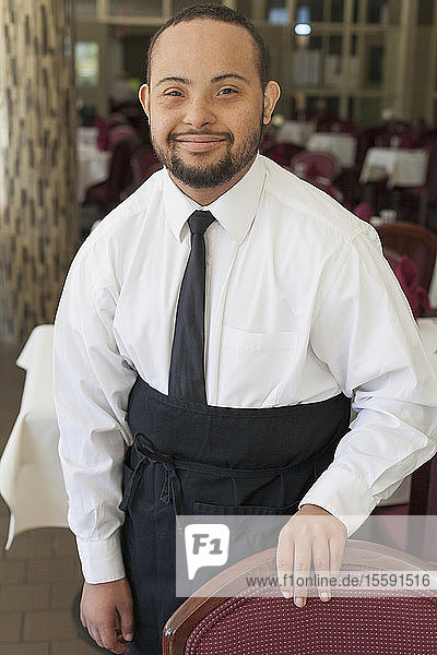 Portrait of African American man with Down Syndrome as a waiter in restaurant