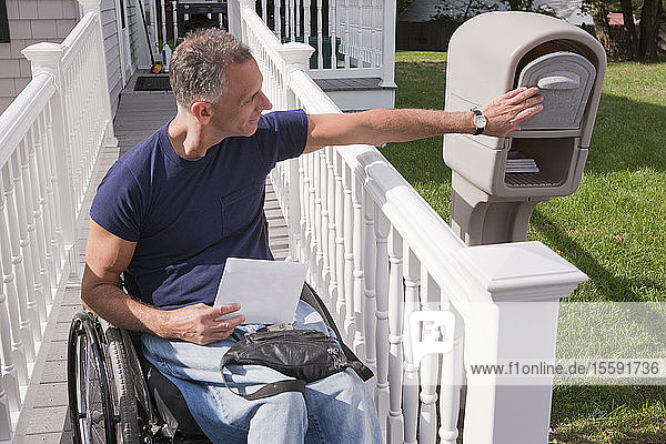 Mann mit Rückenmarksverletzung im Rollstuhl holt seine Post ab