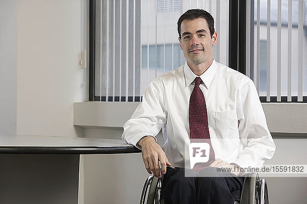 Geschäftsmann mit Querschnittslähmung sitzt in einem Büro