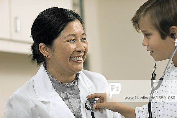 Kleiner Junge hört spielerisch den Herzschlag seines Arztes mit einem Stethoskop ab