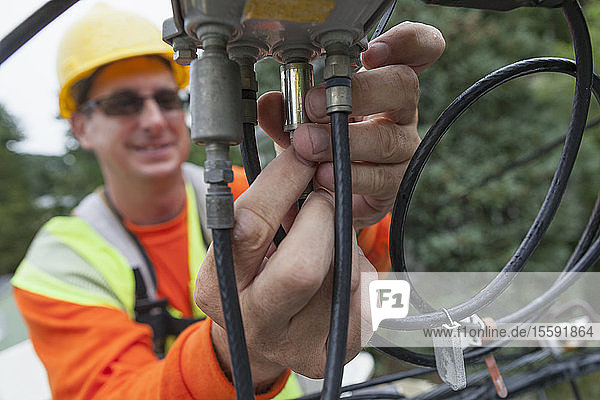 Kabelmonteur beim Anbringen eines Netzfilters an einem Verteilerkasten von einem Eimerwagen aus