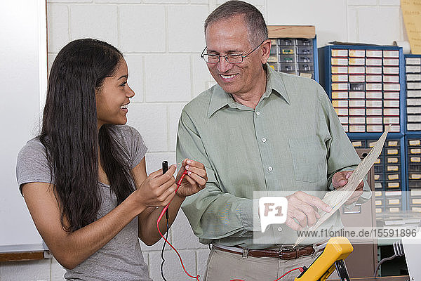 Engineering professor showing a resistor value chart to a student