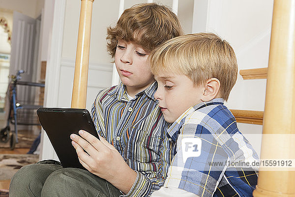 Close-up of two brothers reading a digital tablet