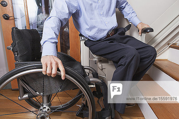 Mann mit Querschnittslähmung steigt in seinen motorisierten Treppenlift ein