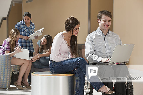 Lehrerin mit Rückenmarksverletzung und Schüler arbeiten an einem Laptop