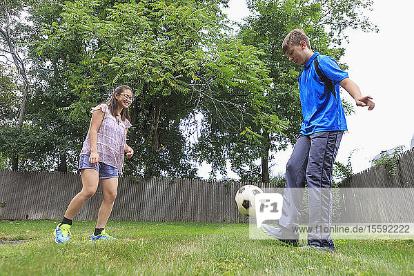 Lernbehindertes Teenager-Mädchen spielt Fußball mit ihrem Bruder