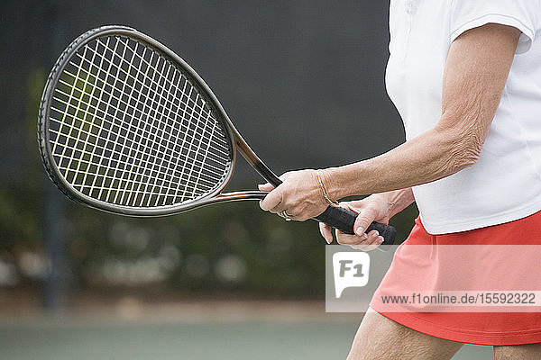 Mid section view of a senior woman playing tennis