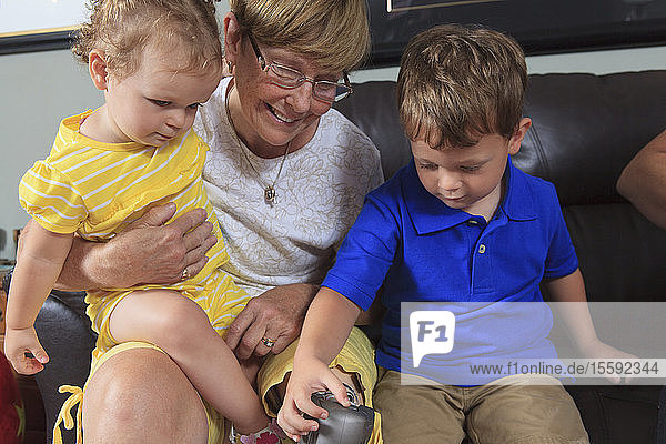 Großmutter mit Beinprothese erlaubt ihren Enkelkindern  mit ihrem Bein zu spielen