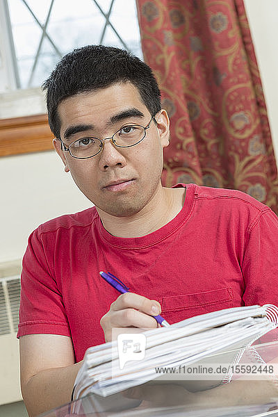 Porträt eines asiatischen Mannes mit Autismus  der an seinen Hausaufgaben arbeitet