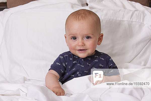 Porträt eines kleinen Jungen  der sich im Bett aufrichtet