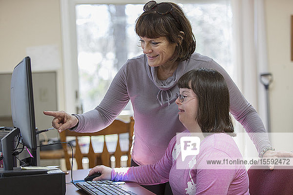 Frau mit Down-Syndrom und ihre Mutter am Computer