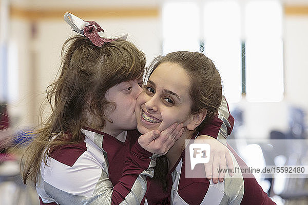 Cheerleader with Down Syndrome kissing another cheerleader